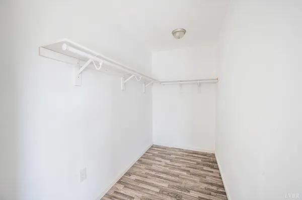 a view of an empty room with wooden floor and a fireplace