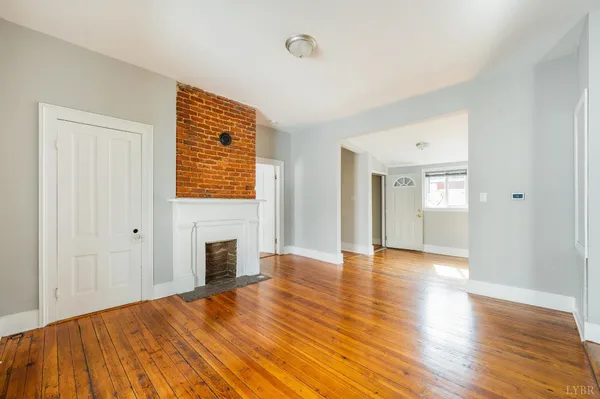 a view of an empty room with a window and wooden floor