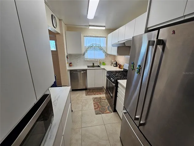 a kitchen with stainless steel appliances granite countertop a refrigerator and a stove