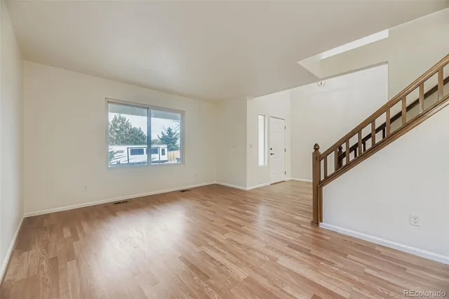 a view of an empty room with wooden floor and entryway