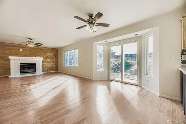 an empty room with wooden floor fireplace and windows