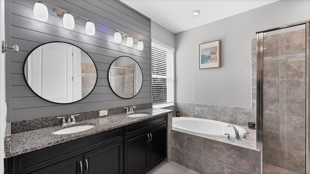 5935 Maidenstone Way Palmetto, FL 34221 - Photo 12 of 52 a bathroom with a granite countertop bathtub a double vanity sink and a mirror
