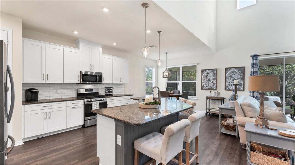 5935 Maidenstone Way Palmetto, FL 34221 - Photo 7 of 52 a large kitchen with a table chairs stove and wooden floor