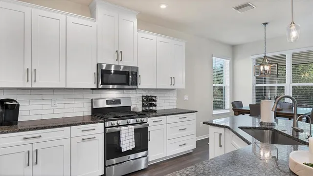 a kitchen with stainless steel appliances granite countertop white cabinets a sink and dishwasher