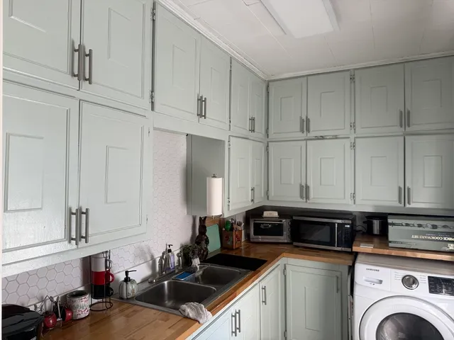 a kitchen with white cabinets and sink