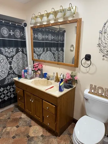a bathroom with a toilet sink vanity granite and mirror