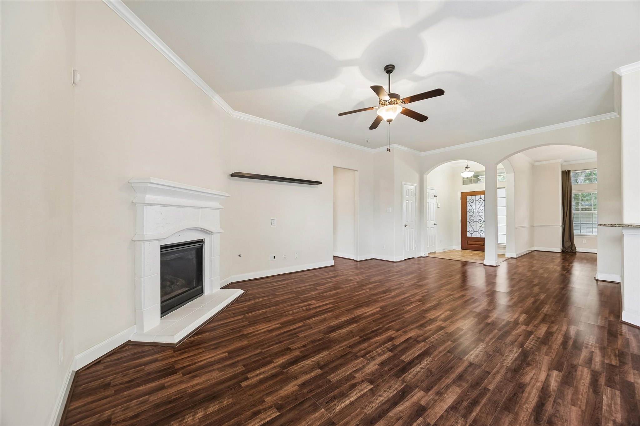 2214 Wembley Way Rosenberg, TX 77471 - Photo 12 of 35 Spacious living area featuring wood-finish flooring, a white mantel fireplace, crown molding, and a ceiling fan