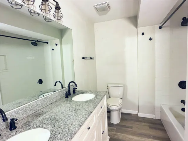 a bathroom with a granite countertop sink toilet and shower