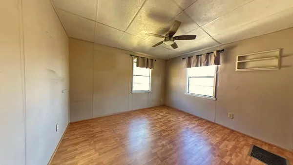 a view of empty room with wooden floor and fan
