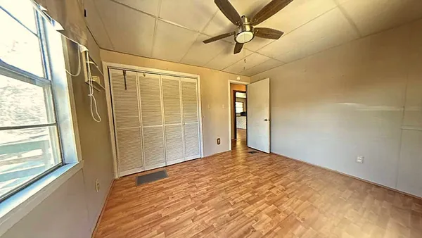 a view of a big room with wooden floor and windows