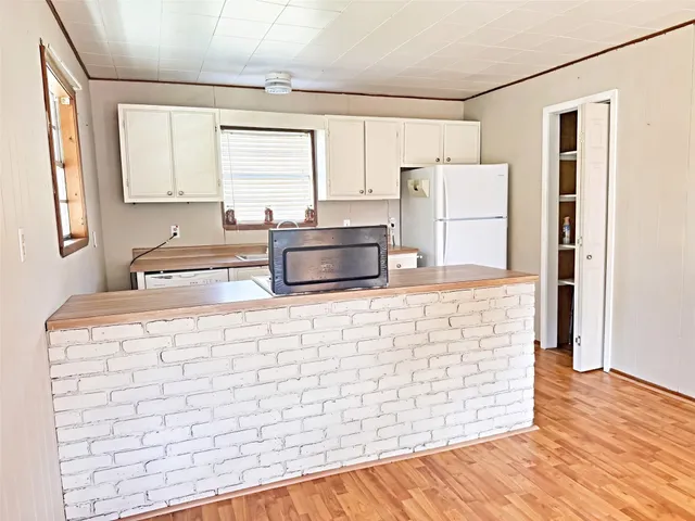 a kitchen with stainless steel appliances granite countertop a sink a stove a refrigerator and island with wooden floors