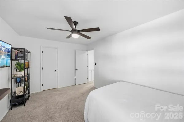 a bedroom with a large bed and a chandelier fan