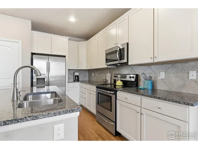 a kitchen with stainless steel appliances granite countertop a sink a stove and white cabinets