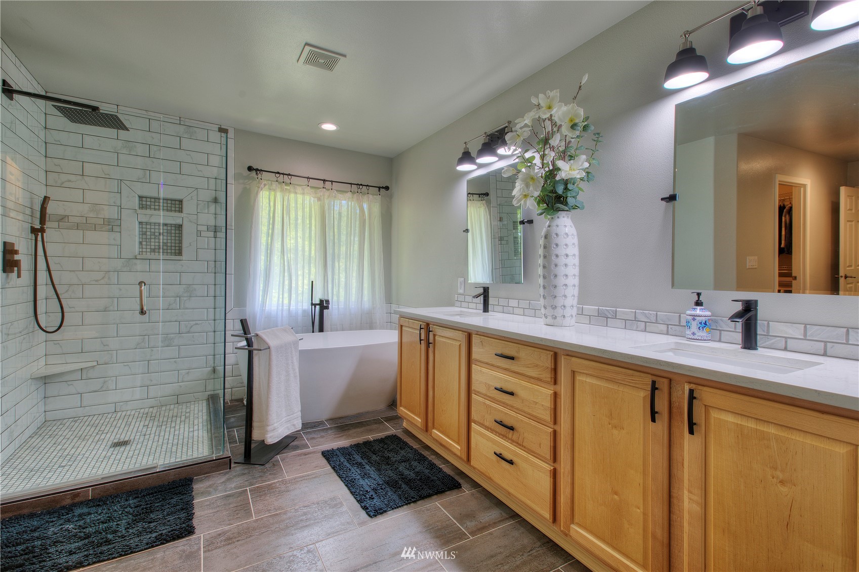 1127 R Street Northwest Auburn, WA 98001 - Photo 23 of 37 a bathroom with a double vanity sink a large mirror a shower and a bathtub
