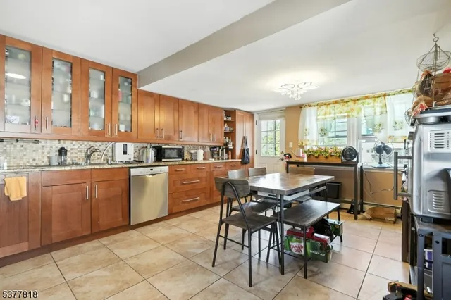 a kitchen with stainless steel appliances kitchen island granite countertop a table chairs sink and cabinets