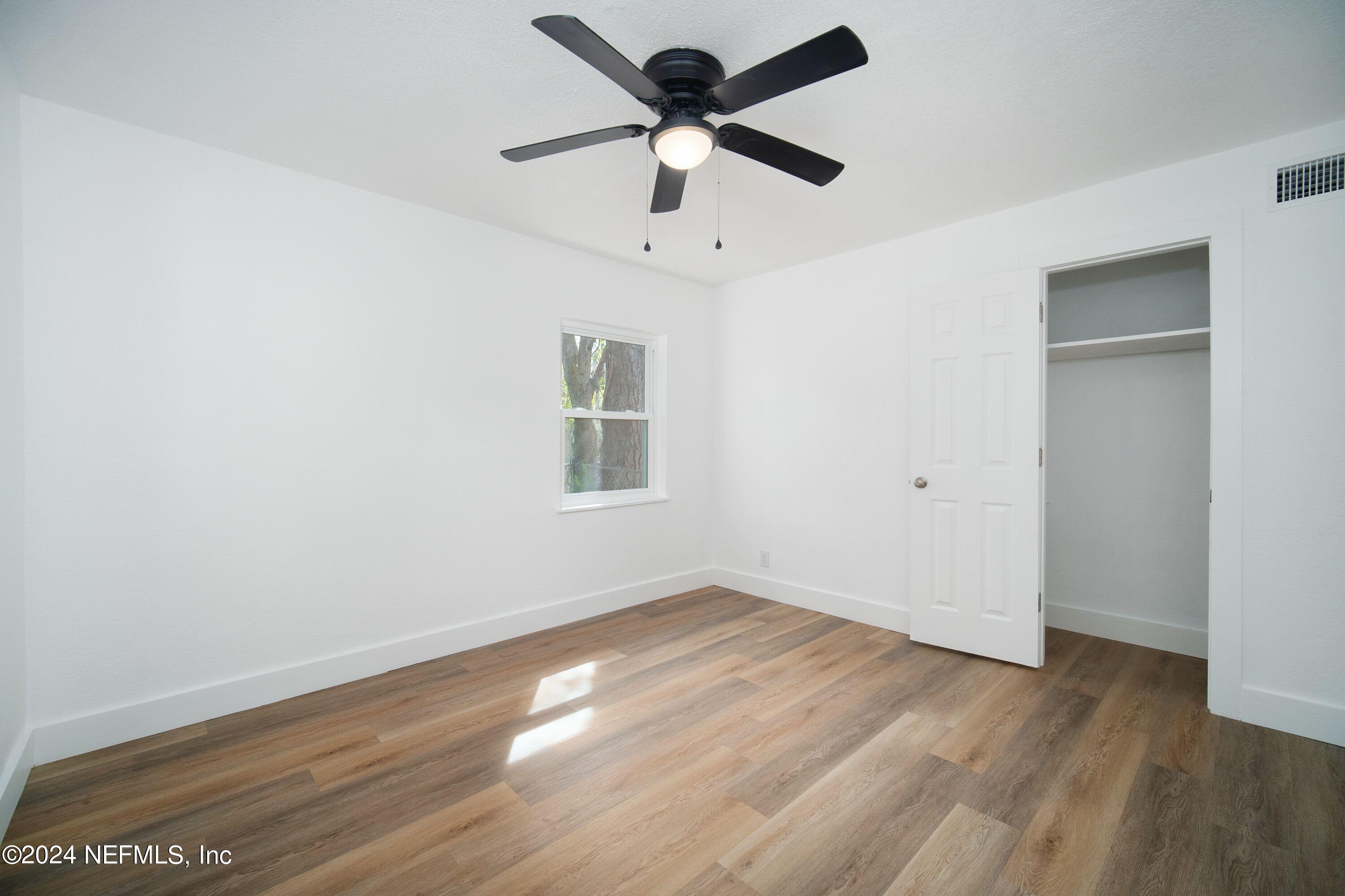 2589 Springmont Street Jacksonville, FL 32207 - Photo 47 of 71 an empty room with wooden floor chandelier fan and windows
