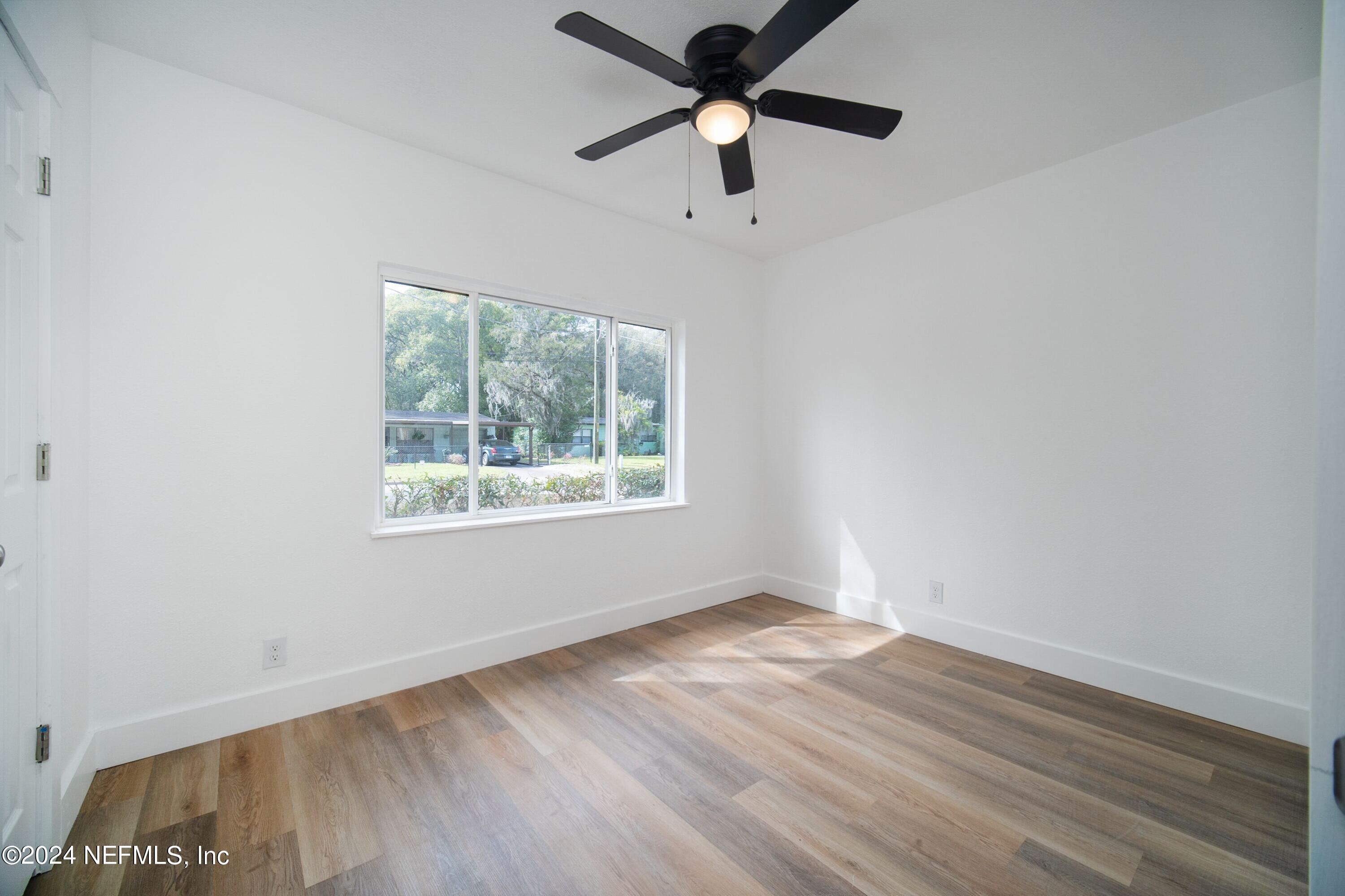 2589 Springmont Street Jacksonville, FL 32207 - Photo 49 of 71 an empty room with wooden floor ceiling fan and windows