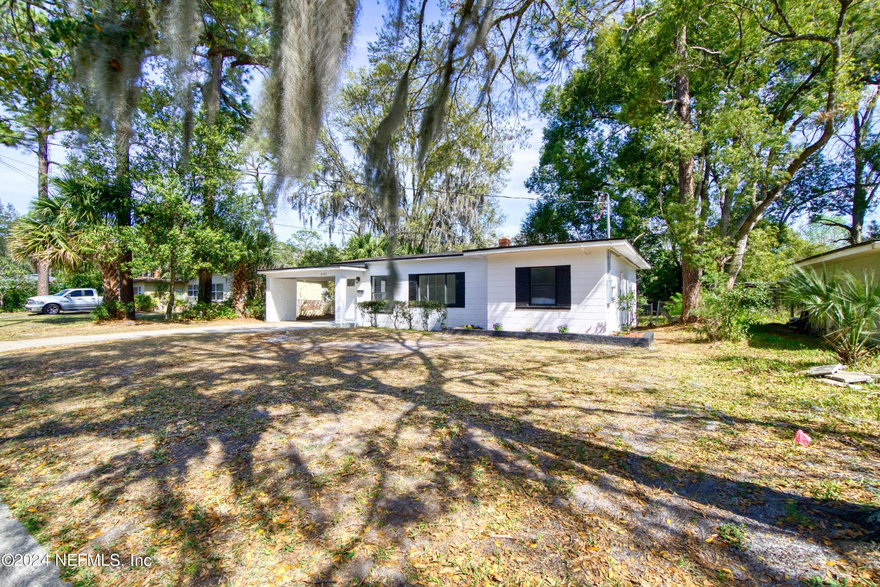 2589 Springmont Street Jacksonville, FL 32207 - Photo 68 of 71 a backyard of a house with large trees and wooden fence