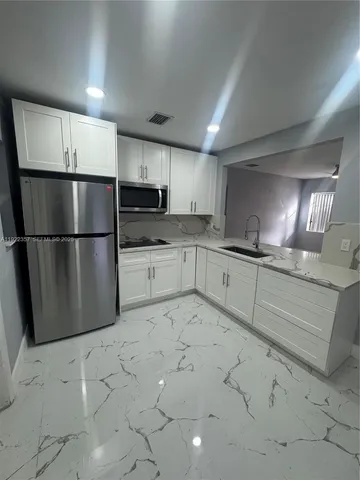 a kitchen with granite countertop a refrigerator and a sink
