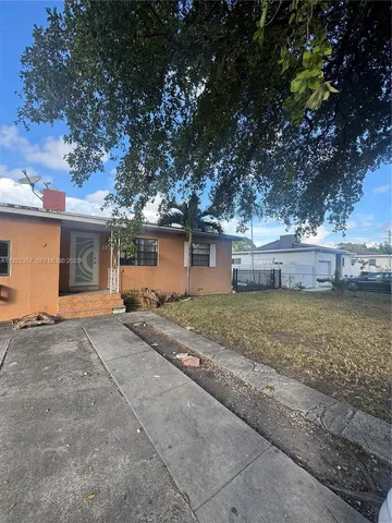 a view of a house with a yard and large tree