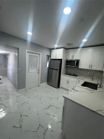 a kitchen with stainless steel appliances a refrigerator a sink a stove a microwave and cabinets