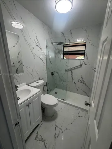 a bathroom with a granite countertop sink toilet and shower