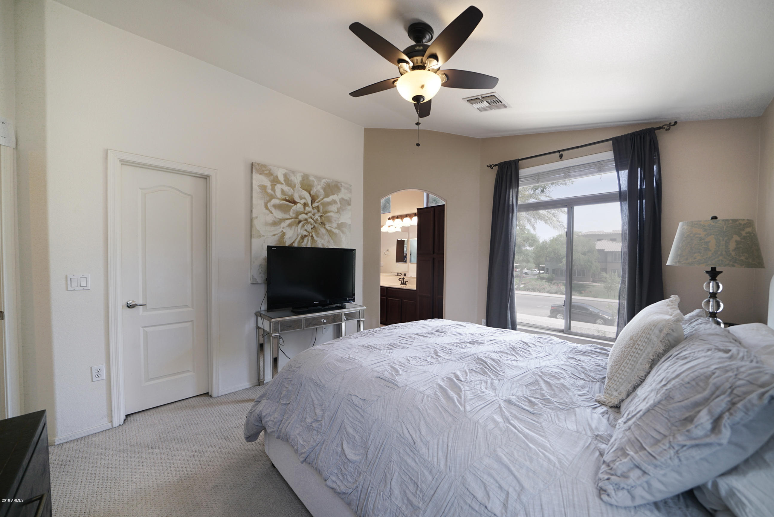 280 South Evergreen Road, Unit 1229 Tempe, AZ 85288 - Photo 15 of 31 a bedroom with a large bed and a flat tv screen on a dresser