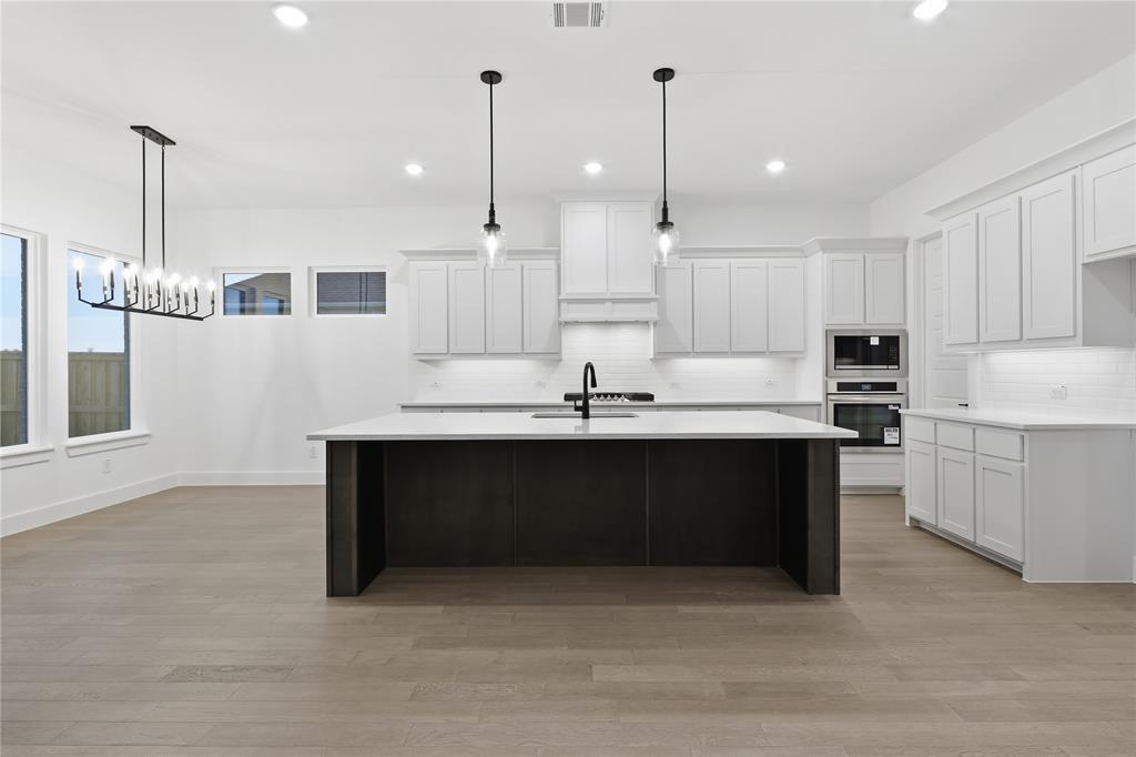 1653 Cedar Elm Way Burleson, TX 76028 - Photo 9 of 26 a kitchen with kitchen island white cabinets and stainless steel appliances
