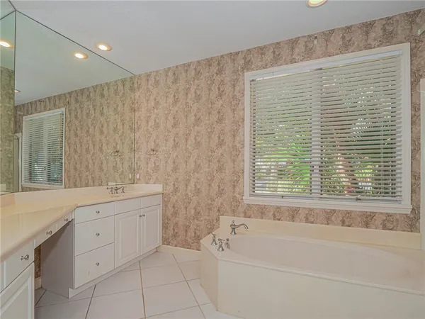 a bathroom with a granite countertop sink a bathtub and next to a window