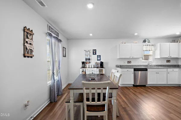 a kitchen with stainless steel appliances granite countertop a stove a refrigerator a sink a dining table and chairs with wooden floor