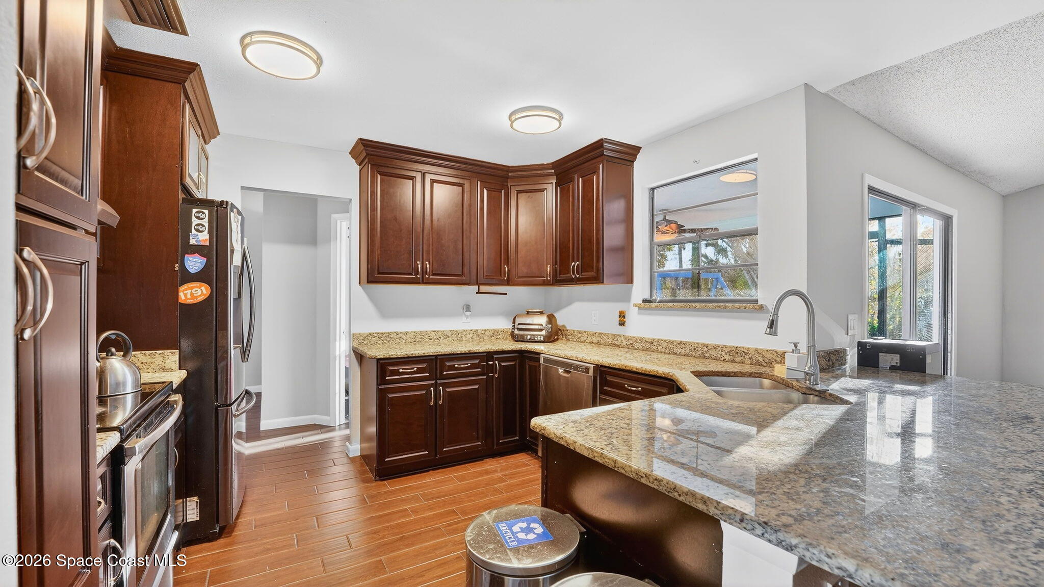 6398 Cable Avenue Cocoa, FL 32927 - Photo 10 of 30 a kitchen with stainless steel appliances granite countertop a sink dishwasher stove and refrigerator with wooden floor
