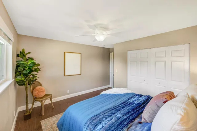 a view of a backyard with table and chairs potted plants and large tree