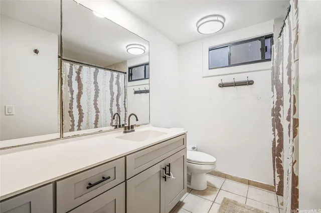 a bathroom with a granite countertop sink toilet and mirror