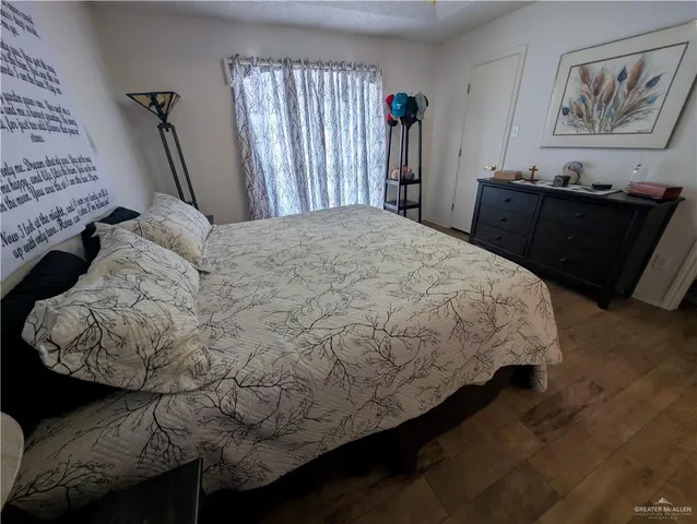 a bedroom with a bed and dresser with wooden floor
