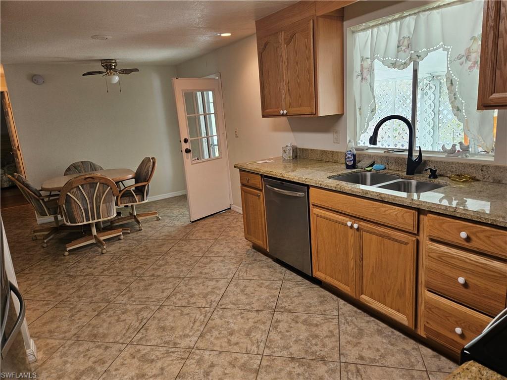 859 Manatee Road Naples, FL 34114 - Photo 14 of 37 Kitchen with light stone countertops, sink, light tile patterned flooring, dishwasher, and ceiling fan