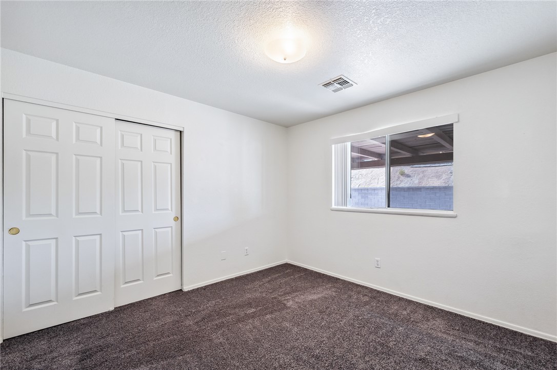 2524 South Ridge Avenue Bullhead City, AZ 86429 - Photo 36 of 64 Unfurnished bedroom featuring dark carpet, a textured ceiling, a closet, and baseboards