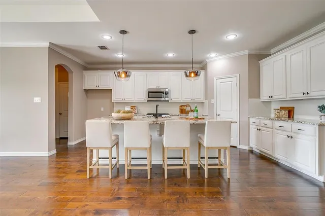 a kitchen with stainless steel appliances kitchen island granite countertop a dining table chairs and view living room