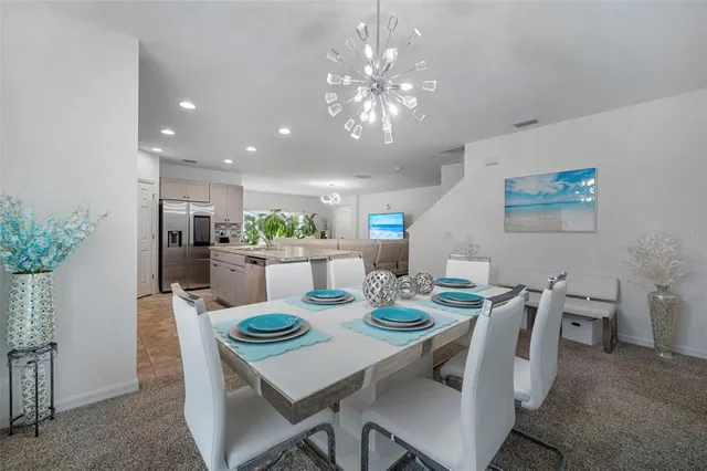 a kitchen with stainless steel appliances granite countertop a table chairs sink refrigerator and cabinets