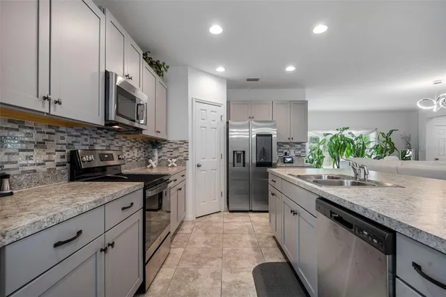 a kitchen with stainless steel appliances granite countertop cabinets sink and refrigerator