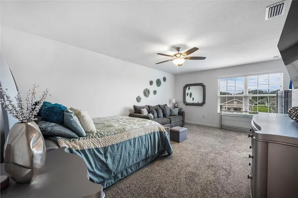 a bedroom with a bed couches and a flat tv screen