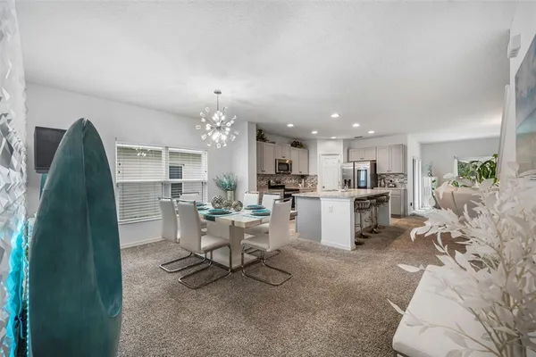 a living room with furniture a chandelier and a dining table