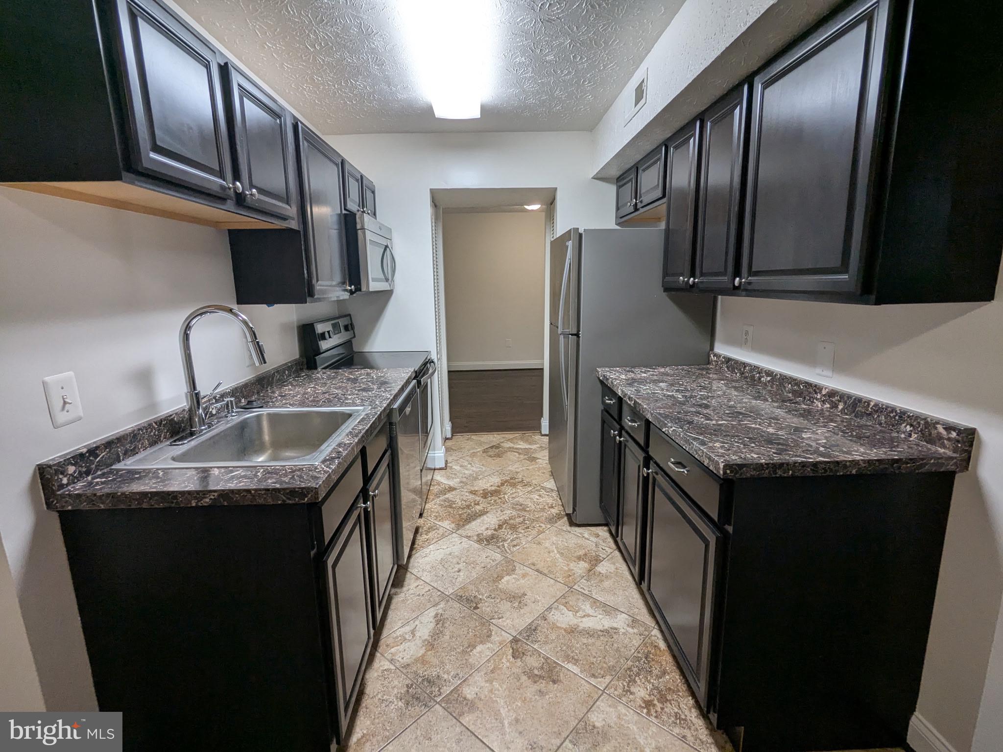 7931 Mandan Road, Unit 623 Greenbelt, MD 20770 - Photo 2 of 9 a kitchen that has a sink a stove and a refrigerator