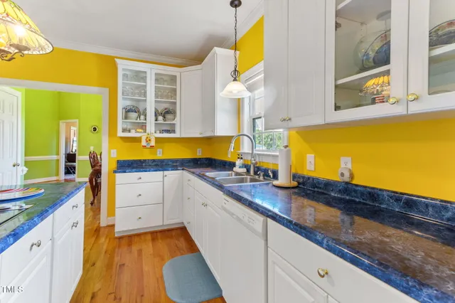 a view of a kitchen with granite countertop a stove a sink a dining table and chairs with wooden floor