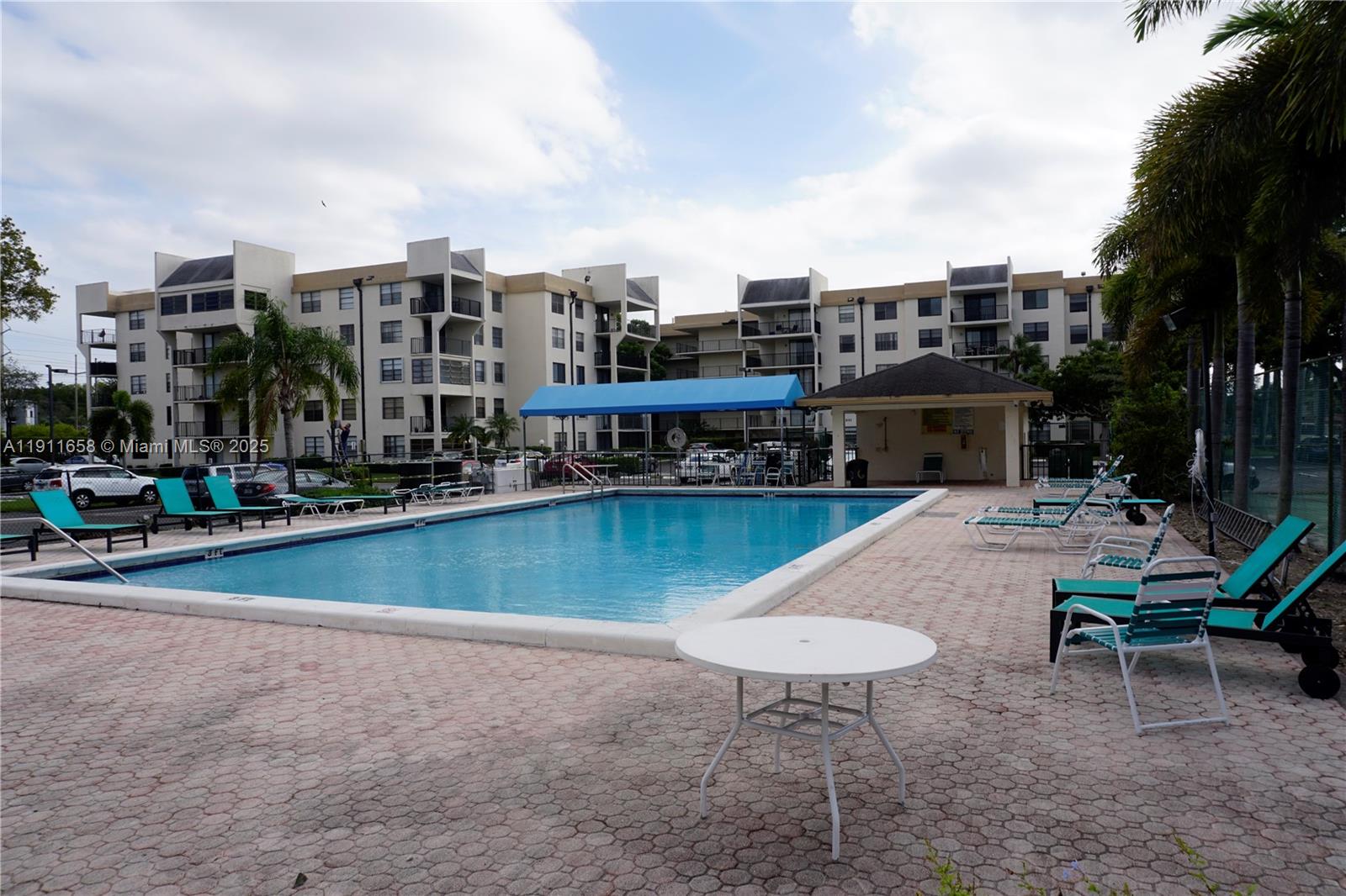 6195 Rock Island Road, Unit 204 Tamarac, FL 33319 - Photo 19 of 23 a view of a swimming pool with lawn chairs and a barbeque