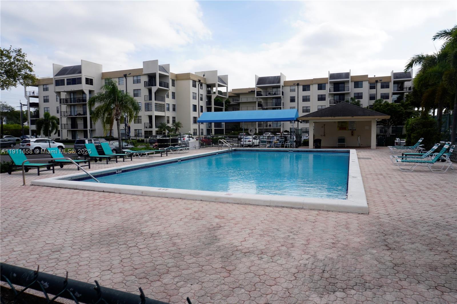 6195 Rock Island Road, Unit 204 Tamarac, FL 33319 - Photo 21 of 23 a view of a swimming pool with a lawn chairs and palm trees