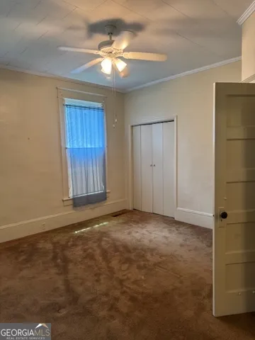 an empty room with closet and fan