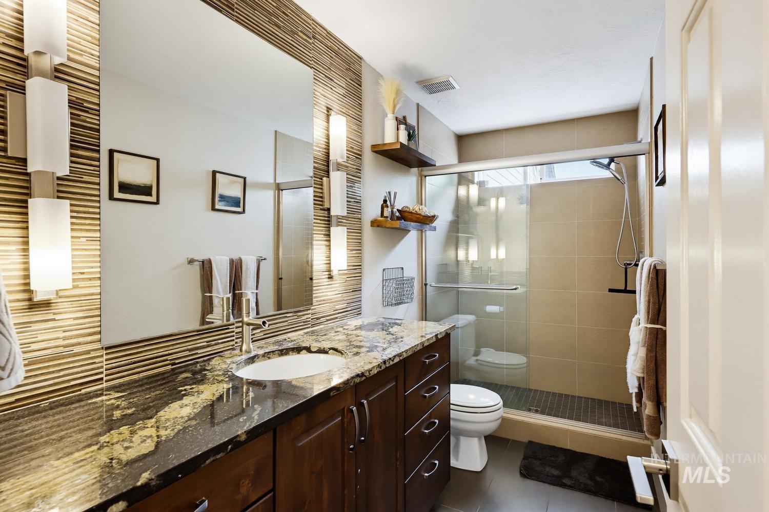 369 South Winthrop Way Boise, ID 83709 - Photo 21 of 50 Bathroom featuring a large vanity with a granite countertop and integrated sink, dark wood cabinetry, a frameless mirror, and modern wall-mounted lighting
