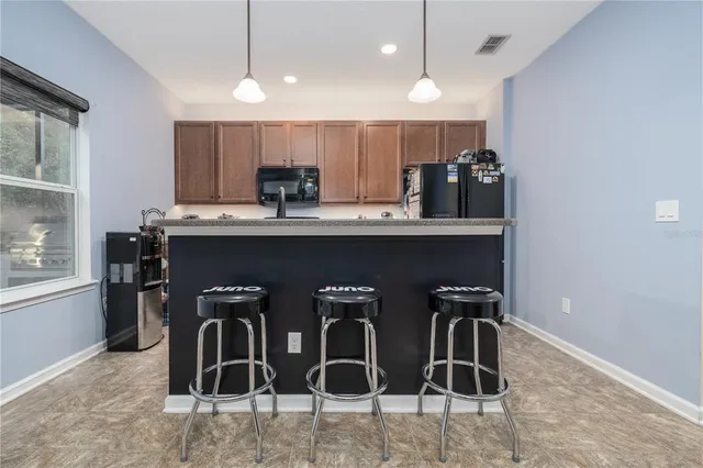 a kitchen with stainless steel appliances kitchen island granite countertop a table chairs in it and wooden floors