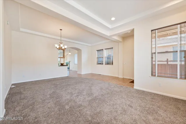 an empty room with windows and chandelier fan