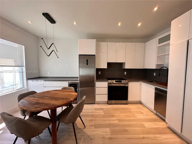 a kitchen with stainless steel appliances kitchen island granite countertop a refrigerator a stove a sink dishwasher and a stove with wooden floor